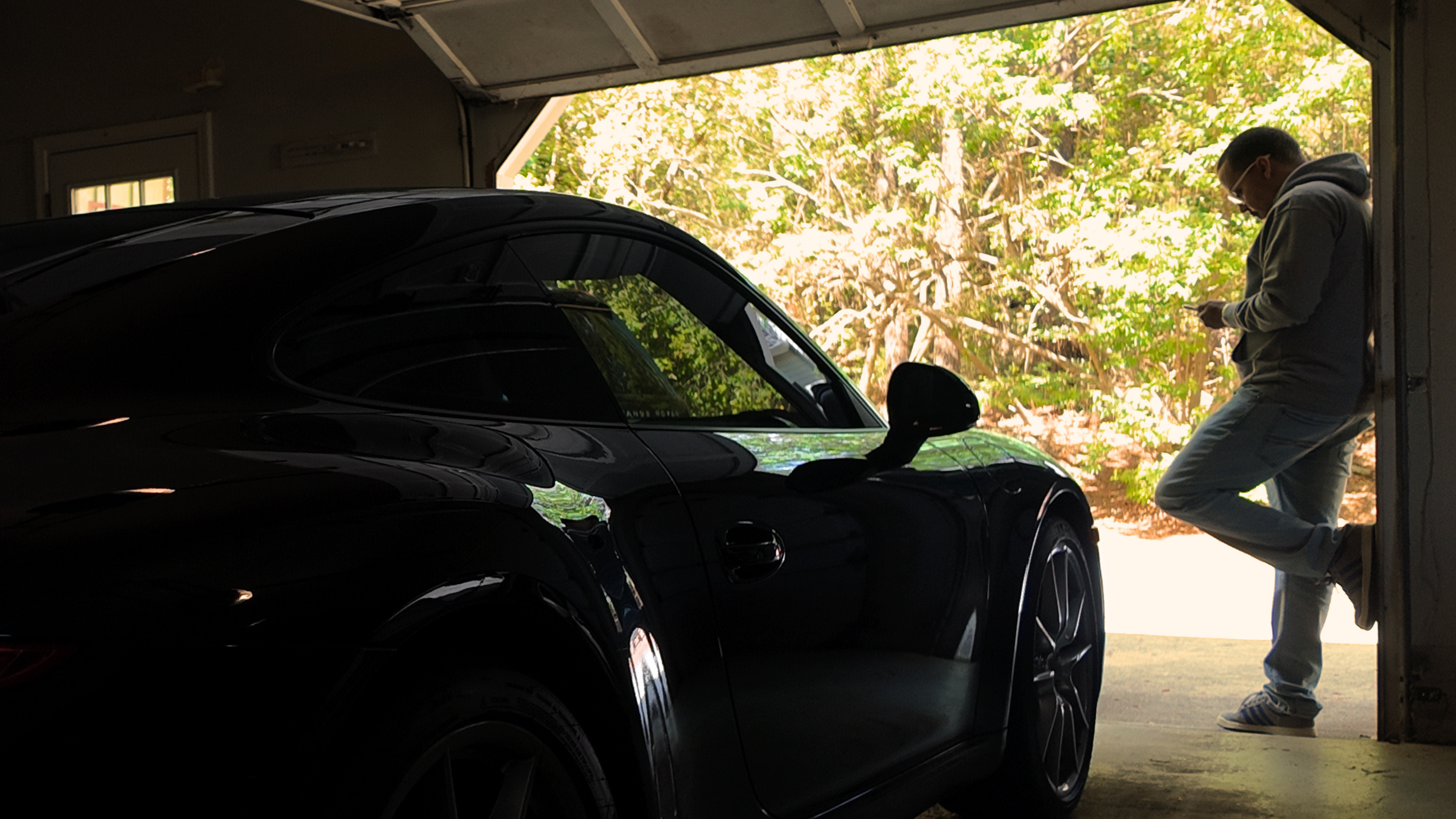 Person exiting a garage with a black sports car